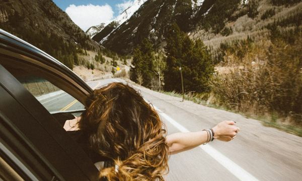 Viajante com o braço para fora da janela do carro na estrada