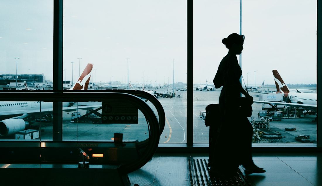 Viajante com mala no aeroporto observando os aviões